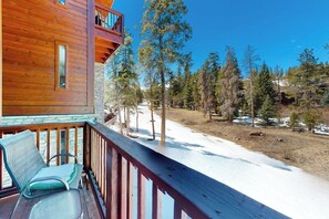 Eine Holzhütte mit einem Balkon mit Blick auf eine verschneite Landschaft und Bäume.
