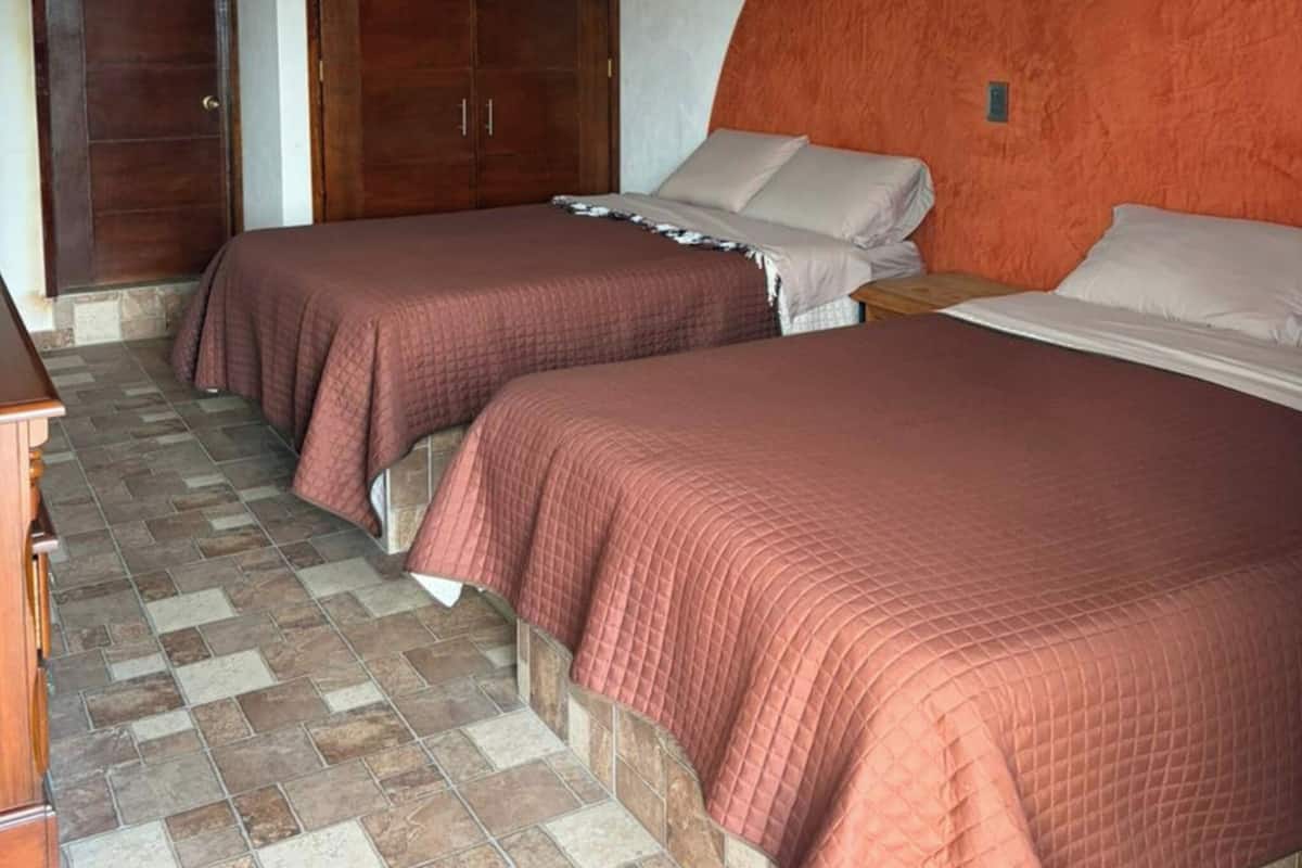 Un dormitorio con dos camas, un armario y suelo de baldosas.