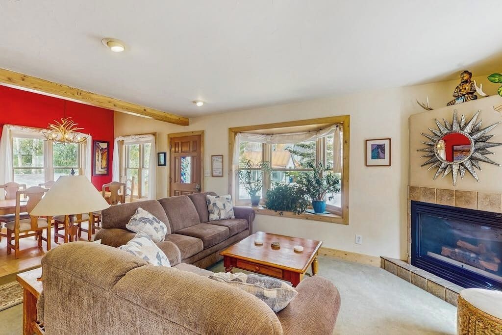 Ein Wohnzimmer mit einer Couch, einem Couchtisch, einem Kamin und großen Fenstern.