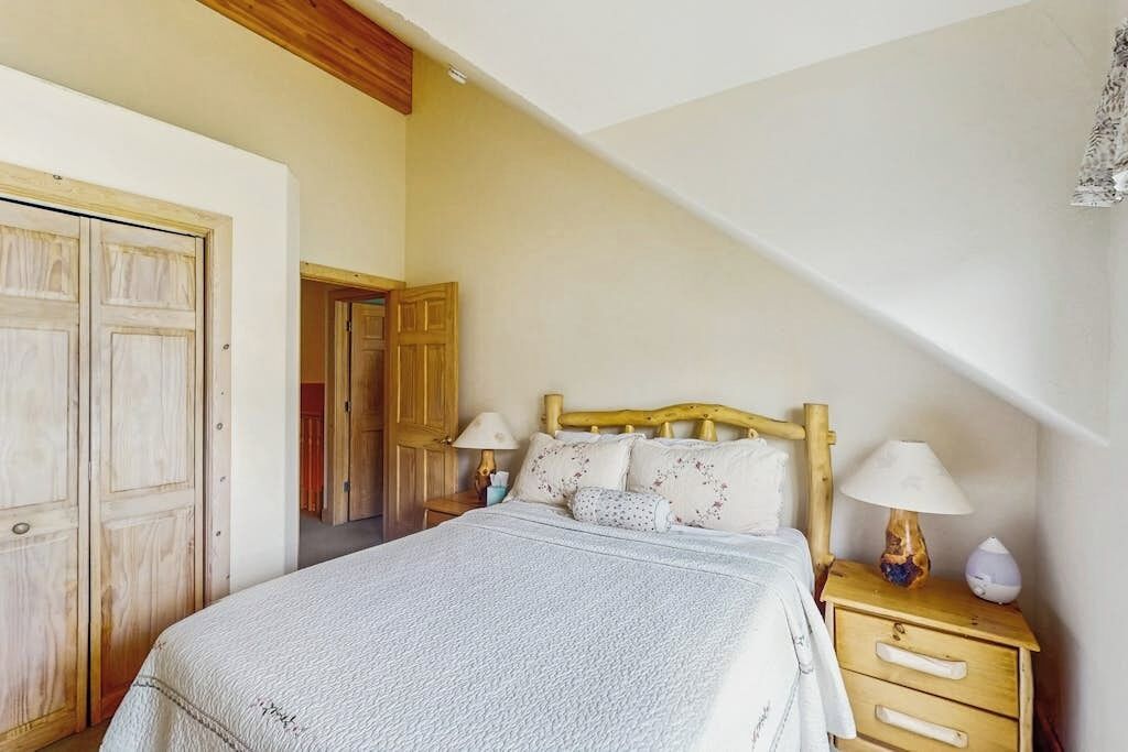 Een slaapkamer met een bed, nachtkastjes, een houten hoofdbord en een kledingkast.