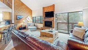 Ein modernes Wohnzimmer mit Kamin, Fernseher und Balkon mit Aussicht.