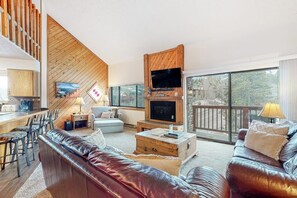 Ein modernes Wohnzimmer mit Kamin, Fernseher und Balkon mit Aussicht.