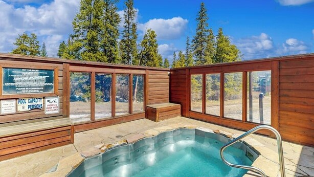 Ein Whirlpoolbereich mit Holzwänden, großen Fenstern und Schild mit der Angaben zur Poolkapazität.