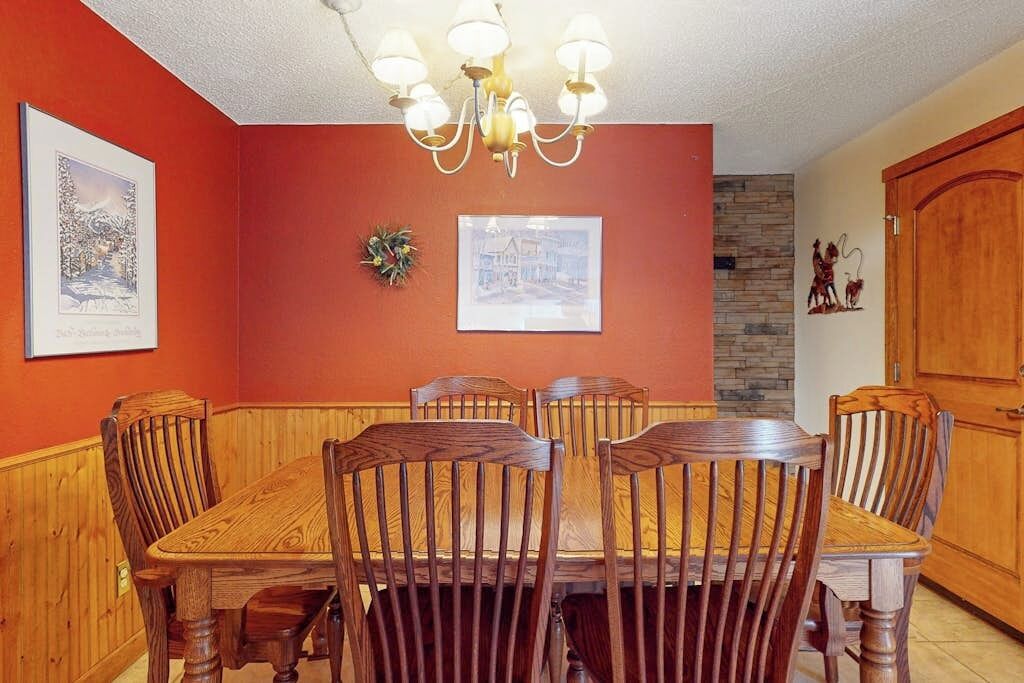 Un coin repas avec une table et des chaises en bois, un lustre et des tableaux encadrés accrochés aux murs.