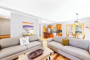 Ein modernes Wohnzimmer mit zwei Sofas, einem Couchtisch und einer Küche im Hintergrund.