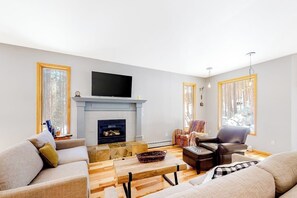 Ein Wohnzimmer mit Kamin, Sofas, einem Couchtisch und einem Fernseher.