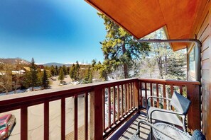 Ein Holzbalkon mit Blick auf eine verschneite Landschaft und Bäume.