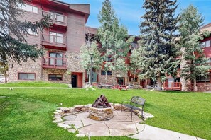 A courtyard with a fire pit, outdoor seating, and a stone building with balconies. - 3rd-floor ski-in/out condo with fireplace, hot tubs, & gym (Breckenridge)