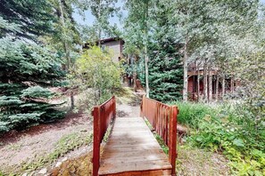 A wooden bridge in a forested area with buildings in the background. - 3rd-floor ski-in/out condo with fireplace, hot tubs, & gym (Breckenridge)