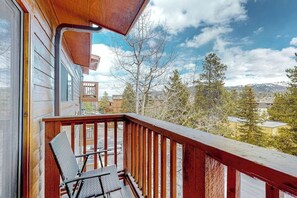A wooden balcony with a view of a town and mountains. - 3rd-floor ski-in/out condo with fireplace, hot tubs, & gym (Breckenridge)