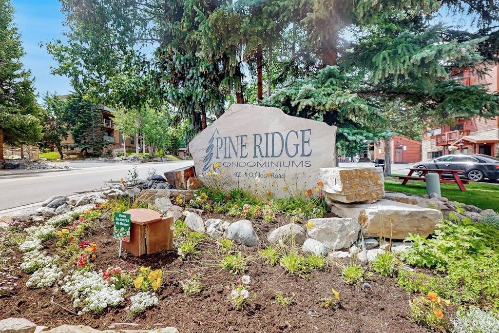 Schild für Pine Ridge Condominiums mit Blick auf eine Straße und umliegendes Grün.