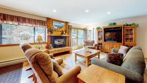 Una sala de estar acogedora con chimenea, televisor y estantería.