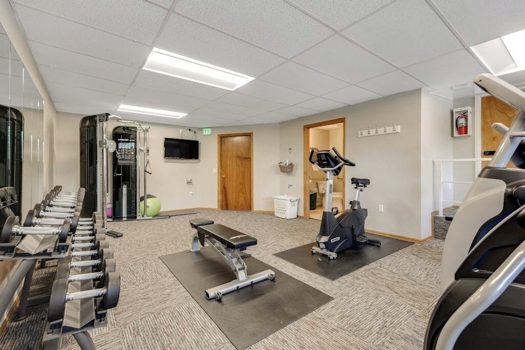 A gym with exercise equipment, a treadmill, and a stationary bike.