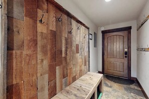 Ein Flur mit Holzwand, einer Bank, einer Tür und einem Kleiderständer.