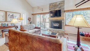 Una sala de estar con chimenea de piedra, televisor y sofá.