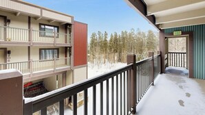 A multi-story building with balconies, a snow-covered ground, and a forest in the background. - Shuttle to lifts from condo w/ panoramic views (Breckenridge)