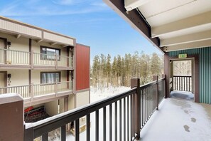 A multi-story building with balconies, a snow-covered ground, and a forest in the background. - Shuttle to lifts from condo w/ panoramic views (Breckenridge)