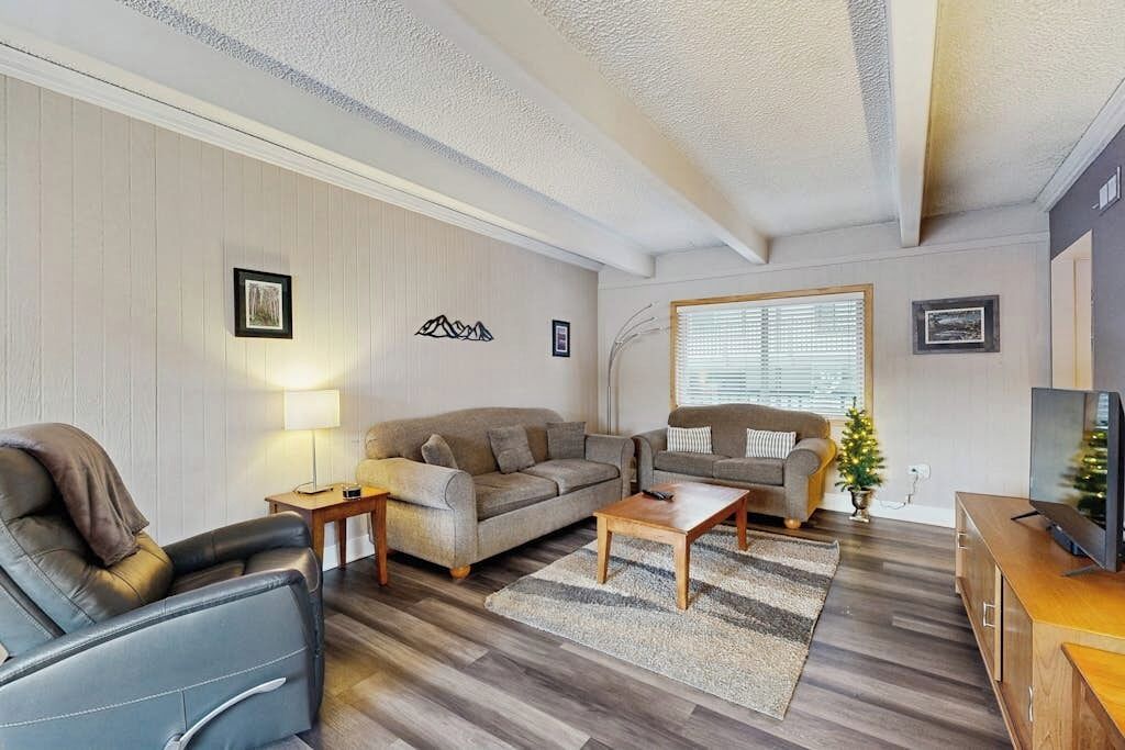 Ett vardagsrum med två soffor, ett soffbord, en tv och ett litet julgran.