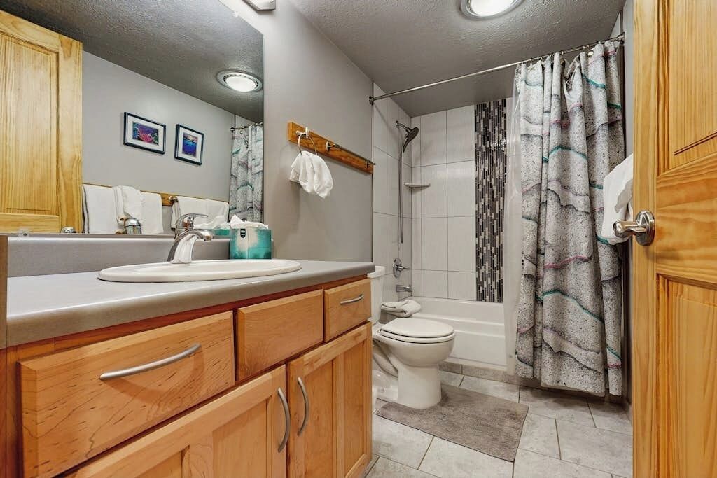 Un baño con tocador de madera, lavamanos, inodoro, ducha y bañera.
