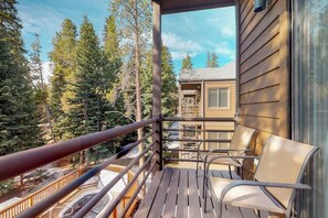 A wooden deck with chairs, a railing, and a view of trees. - Condo on the Four O'Clock Run with EV charger, two blocks to Main Street (Breckenridge)