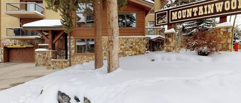 Un immeuble à plusieurs étages, doté d’une façade en pierre, d’une enseigne indiquant « MOUNTAINWOOD » et d’un sol recouvert de neige.