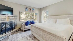 Un dormitorio con una cama grande, chimenea, sofá y televisor.