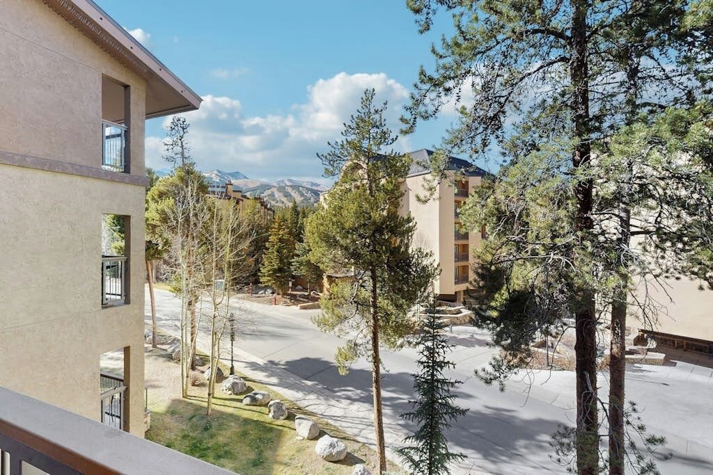A building with multiple windows, a balcony, and a view of a mountainous landscape.