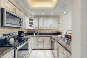 Una cocina moderna con armarios blancos, una estufa negra, un microondas y un lavamanos.