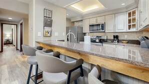 Una cocina moderna con encimera de granito, electrodomésticos de acero inoxidable y una zona de bar con taburetes.