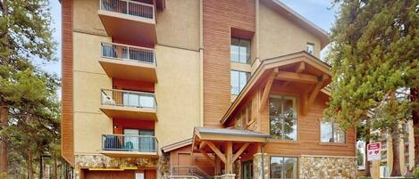 A multi-story building with balconies, a stone facade, and a wooden entrance.