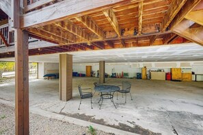 Un garage ouvert avec un sol en béton, des chaises en métal et une structure de plafond en bois.