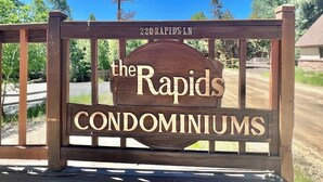 Een houten bordje met 'the Rapids Condominiums' erop, bevestigd aan een hek.