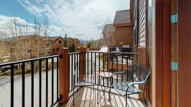 A balcony with a metal railing, two chairs, and a small table. - Townhouse with a ski lodge feel with mountain view, W/D, fireplace & balcony (Keystone)