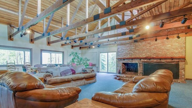 Ein geräumiges Wohnzimmer mit Ledersofas, einem Holztisch und einem Kamin aus Backsteinen.