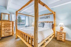 Ein Bett mit Baldachin und Holzrahmen, ein Nachttisch mit Lampe sowie ein Schild an der Wand.