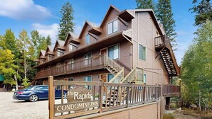 Een meerlaags houten gebouw met balkons en een bord waarop 'The Rapids Condominiums' staat.