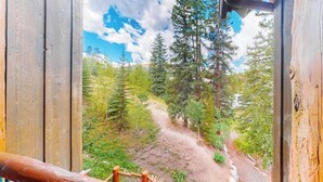 Una terraza de madera con vistas a una zona boscosa y un sendero de tierra.