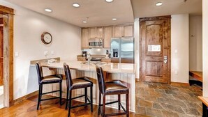 Una cocina con una isla central, armarios de madera, un refrigerador de acero inoxidable y un reloj en la pared.