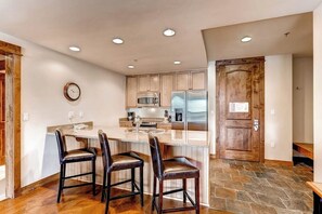 A kitchen with a central island, wooden cabinets, a stainless steel refrigerator, and a clock on the wall. - Amazing BlueSky villa with game room, pool, & hot tub access - ski-in/ski-out (Breckenridge)