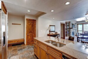 A kitchen with granite countertops, wooden cabinets, a built-in oven, and a stone backsplash. - Amazing BlueSky villa with game room, pool, & hot tub access - ski-in/ski-out (Breckenridge)