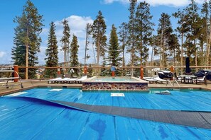 Ein Poolbereich mit Liegestühlen, einem kleinen Pool und Blick auf hohe Bäume und Berge.