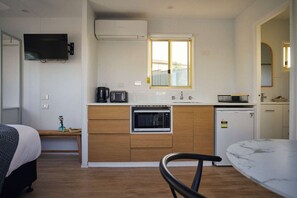 Una cocina compacta equipada con microondas, cafetera y un refrigerador pequeño.