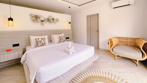 A modern bedroom with a large bed, bedside tables, a wicker sofa, and a wall-mounted air conditioner. - Canggu Luxury Villa – Private Pool (Badung)