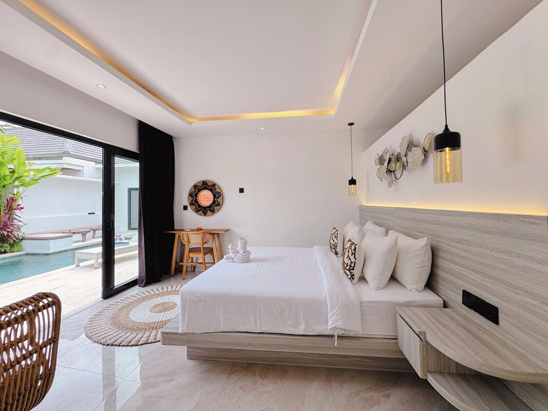 A modern bedroom with a large bed, a desk, and a view of a swimming pool.