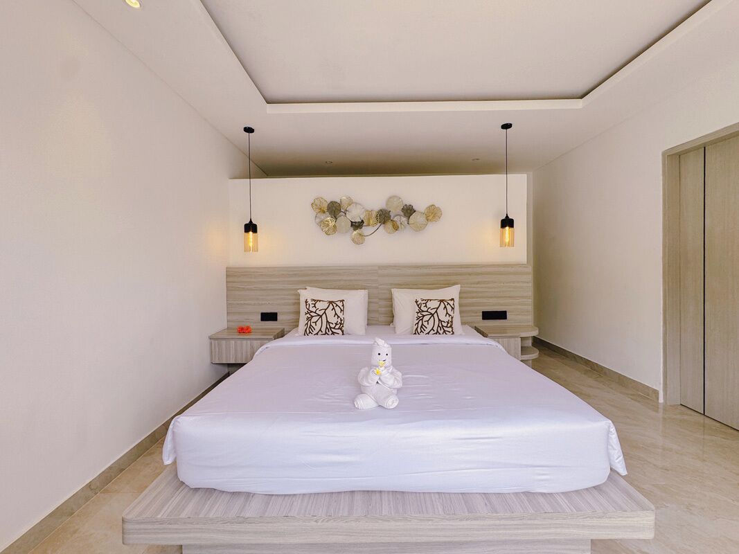 Una habitación de hotel moderna con una cama grande, una mesita de noche, un adorno en la pared y una lámpara colgante.