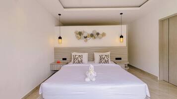 Una habitación de hotel moderna con una cama grande, una mesita de noche, un adorno en la pared y una lámpara colgante.