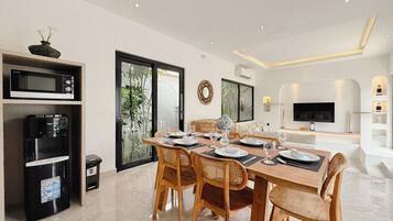 A modern dining area with a wooden table set for four, surrounded by wicker chairs.