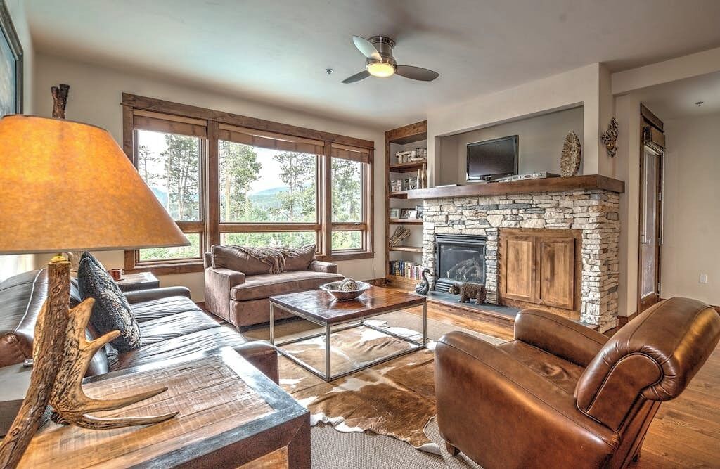 A living room with a fireplace, leather furniture, and a large window.
