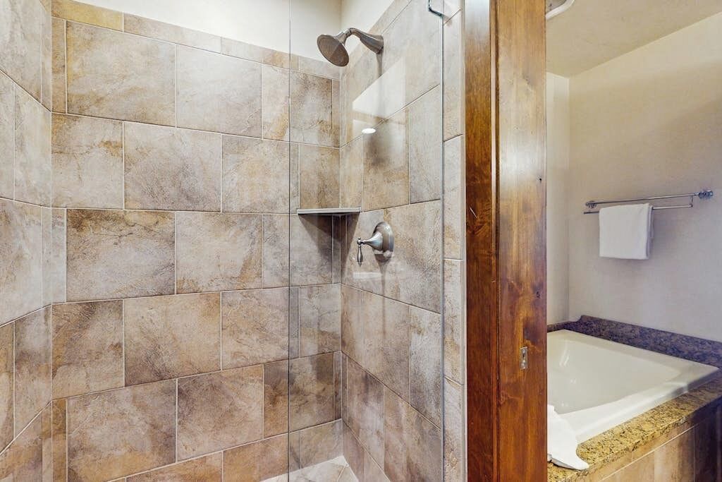 Un baño con ducha, bañera y tocador con toallero.
