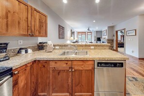 A kitchen with wooden cabinets, granite countertops, a dishwasher, and a window. - Walk-to-lift condo with gas fireplace, hot tubs, pool, gym & steam room (Breckenridge)